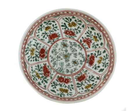 A Chinese wucai plate, Kangxi (1662-1722), of circular form, the centre painted with blossoming prunus by a rock, surrounded 