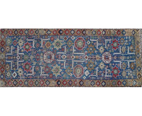 A tribal wool runner, late 19th/ early 20th century, the blue field woven with large floral motifs, within a border of repeat