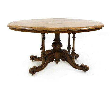 A Victorian walnut centre table, late 19th century, the oval quarter veneered top with a scalloped edge raised on a cluster c