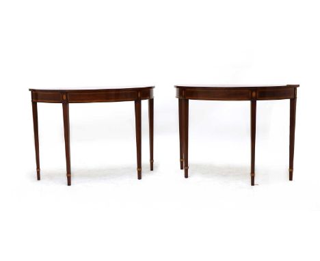 A pair of George III style inlaid mahogany console tables, with segmented veneered demi line tops raised on slender square ta