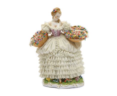 A Dresden Sitzendorf porcelain lace figurine of a flower seller, late 19th century, the lady with fine lace dress raised on a