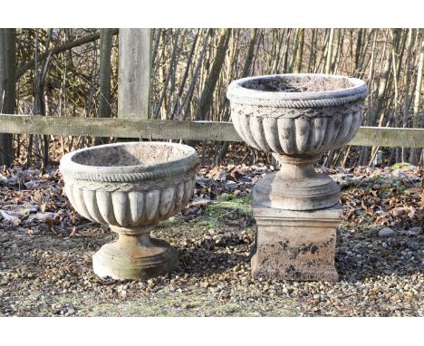 A pair of composite stone garden urns, late 20th century, each of sectional form, with gadroon moulding on a spreading circul