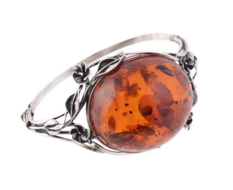 
	
		A clarified amber and silver coloured hinged bangle, the oval clarified amber cabochon measuring approximately 4.4cm x 3