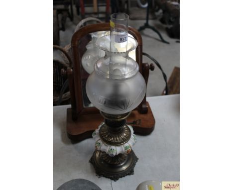 An ornate brass and ceramic oil lamp with etched glass shade
