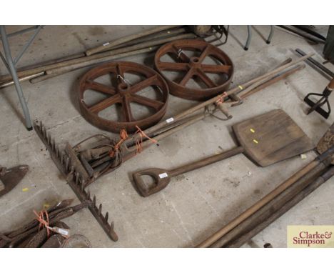 A quantity of long handled tools, including wooden rake, pitch fork etc.