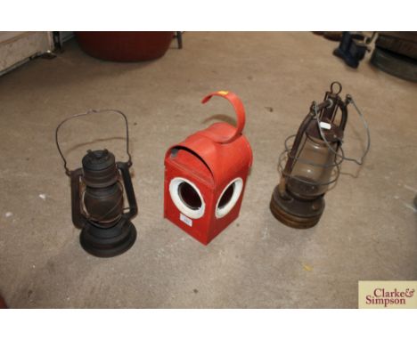 A vintage red road warning lamp and two hurricane lamps