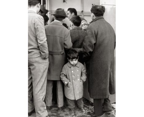 Cattanao, Mario -- Boy in crowd. 1964. Vintage ferrotyped gelatin silver print on doubleweight Agfa paper. 40 x 29,5 cm. Phot