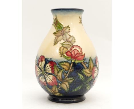 A Moorcroft vase, depicting mauve florals, set against a cream and navy backdrop, in a pattern reminiscent of Oberon and Bram