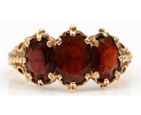 A 9ct gold vintage garnet three stone ring with scroll patterned shoulders, cannot date due to resizing, J 1/2, largest garne