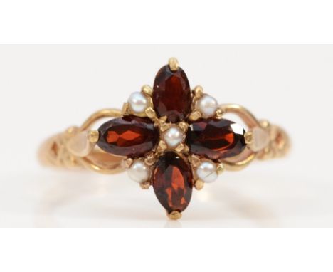 A 9ct gold garnet and seed pearl floral cluster ring with patterned openwork shoulders, P 1/2, 2.5g