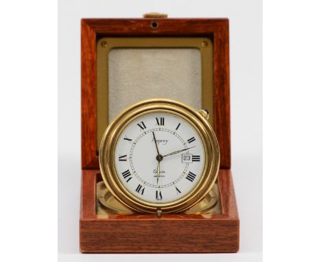 Asprey, a gilt brass circular travel alarm clock with date aperture, synthetic sapphire crown, hours in a mahogany and brass 