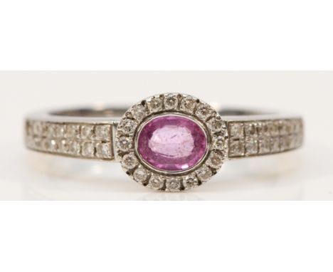 An 18ct white gold pink sapphire and diamond dress ring, central sapphire surrounded by brilliant cut diamonds and diamond se