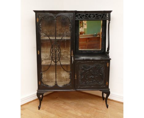 An Edwardian ebonised Rococo style display cabinet, having moulded cornice above a glazed astragal door, mirror backed open s
