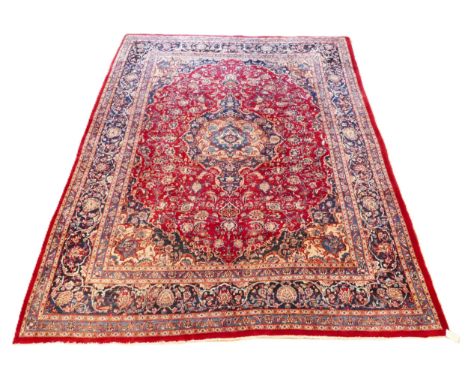 A late 19th century Persian hand woven carpet, having a terracotta ground with central blue medallion, stylised floral motifs