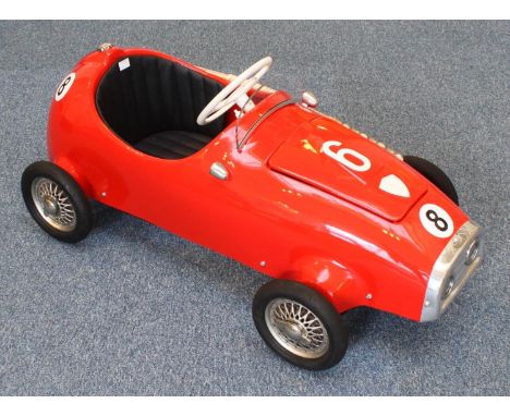 A restored vintage 1960's Pines 'Monza' pedal car, with stitched seat, chrome detailing and hinged bonnet enclosing engine ba