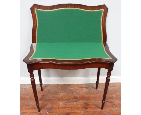 A reproduction mahogany folding card table of serpentine form, with green baize, on turned supports 