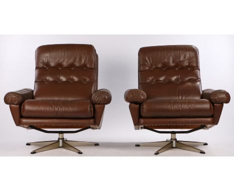 Pair of 1970's brown leather upholstered swivel arm chairs, with button backs, armrests and seats, on chrome bases