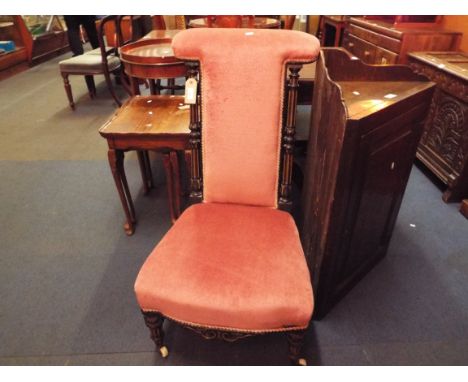 A late Victorian prie-dieu chair, the padded back flanked by ebonised turned fluted supports, the serpentine seat resting on 