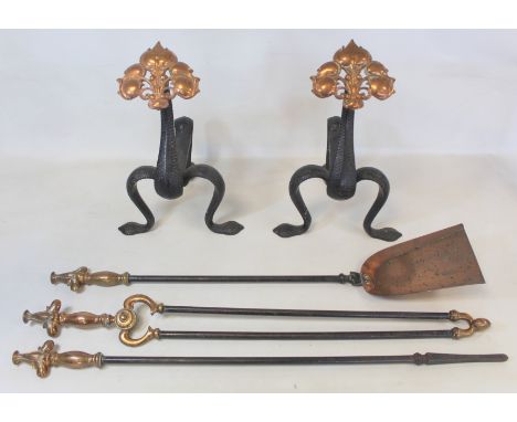 Pair of Art Nouveau wrought iron firedogs with pierced copper lobed foliate finials on stippled strap supports with a set of 