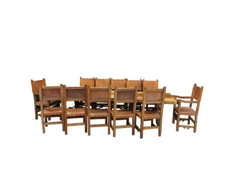 A LARGE 17TH CENTURY STYLE SPANISH OAK REFRECTORY TABLE AND TWELVE CHAIRS. the table on shaped legs with cast iron scrolled t