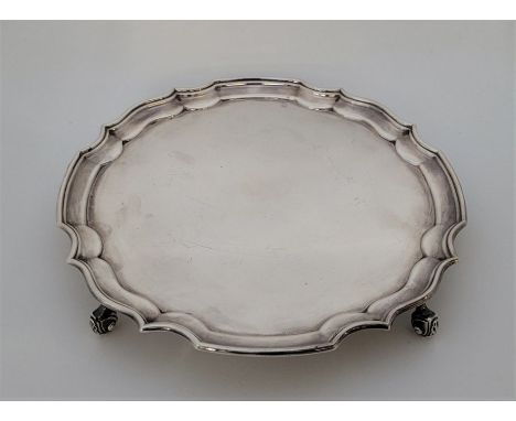 A silver circular salver, by A Chick &amp; Sons Ltd, London 1975, with stepped scrolled border, raised upon quadruple support