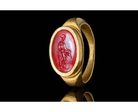 Ca. AD 150 - 300.A gold 22 ct ring with a shallow D-section hoop. It is enlarged on the shoulders and connected to an oval be