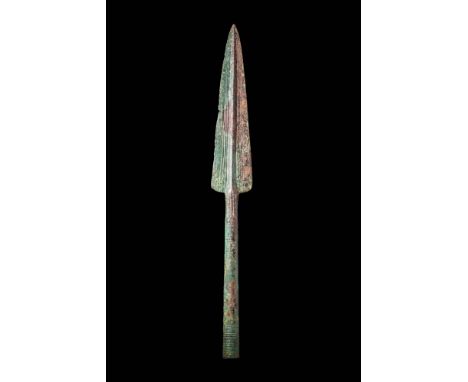 Ca. 800 - 600 BC.A bronze spearhead with a triangular blade, decorated with engraved linear geometric motifs. The long socket