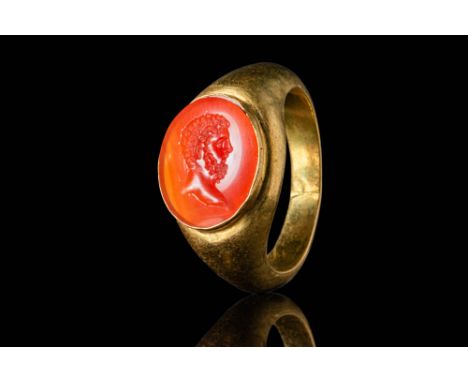 Ca. AD 100 - 300.A gold ring with a D-section hoop enlarged on the shoulders to form an oval bezel securing a carnelian intag