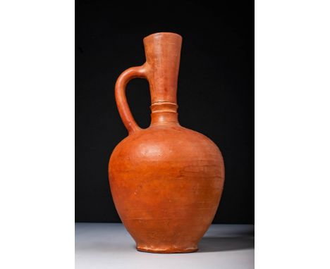 Ca. 100 BC - AD 100.A pitcher formed of rich, reddish-brown terracotta, featuring a rounded body that widens at the shoulder 
