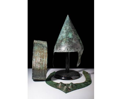 Ca. 800 - 700 BC.A collection of bronze body armour including a bronze helmet in conical form, crafted from a single sheet of