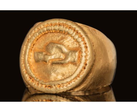 Ca. AD 100 - 200 .A gold ring composed of a flat-section hoop with expanded shoulders, featuring a central raised design. The