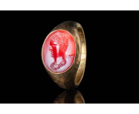 Ca. AD 100 - 200.A gold ring with a D-section hoop enlarged on the shoulders to form an oval bezel securing a carnelian intag