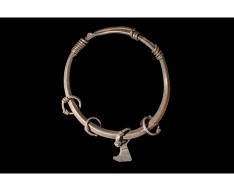 Ca. AD 800 - 1100.A silver bangle with a hollow hoop featuring overlapping ends that taper into wires twisted in a spiral aro