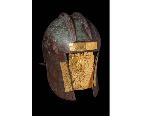 Ca. 700 - 600 BC.A war helmet made of hammered bronze sheet, with a rectilinear opening for the face and long, pointed cheek 