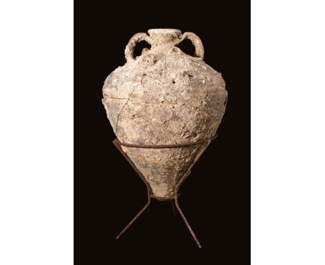 Ca. 600 - 400 BC.A pottery amphora with a conical base, smooth body, tubular neck and collared rim, and a pair of bifurcated 