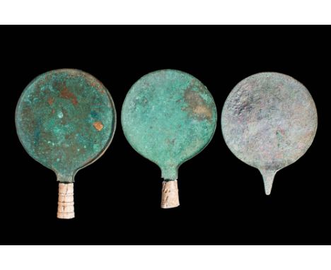 Ca. 400 BC.A collection of three bronze mirrors. The round discs have a slightly concave body with a short rim and a small ta