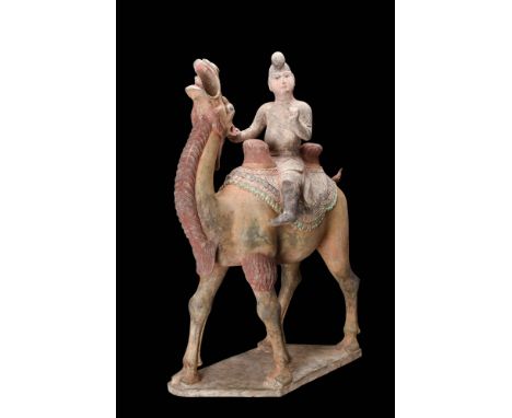 Ca. AD 618 - 907.A terracotta sculpture of a camel with its rider seated atop. The figure, portrayed as a young man, is dress