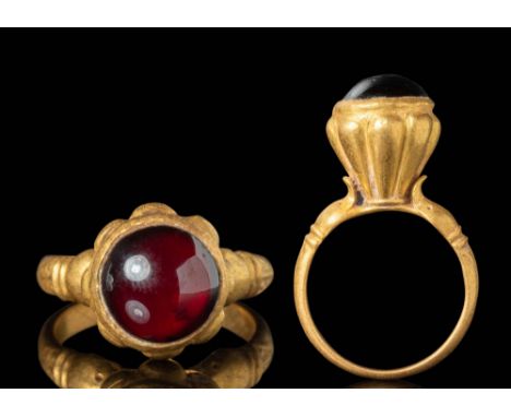 Ca. AD 100 - 300.A Roman gold ring with embellished shoulders depicting the head of two dolphins. The ribbed bezel secures a 