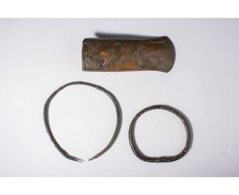 Ca. 1200 - 800 BC.A collection of three bronze artefacts. The first is a torc with a tubular-sectioned shank tapering to term