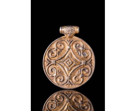 Ca. AD 800 - 1100.A gilded silver medallion, circular in shape and adorned with a central cruciform motif surrounded on all f