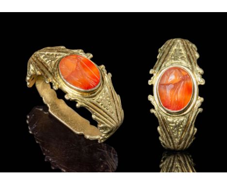 Ca. AD 300.A solid gold ring with an angular hoop, enlarged at the shoulders and embellished with double volutes and geometri
