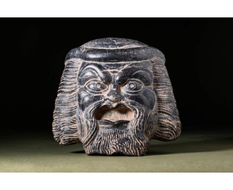 Ca. AD 100.An impressive black stone theatre mask with realistically rendered facial features. It has a coiffure featuring cu