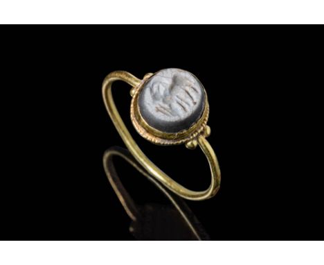 Ca. AD 300 - 500.A gold ring with a solid tubular round hoop embellished with two gold pellets on each shoulder, connected to