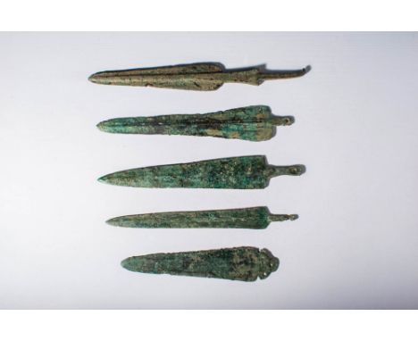 Ca. 1200 - 600 BC.A collection of five bronze weapons. The first is a spearhead with a short curved tang and a large blade fi