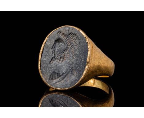 Ca. AD 50 - 100.A gold 21 ct ring with a shallow D-shaped hoop enlarged on the shoulders to form a round bezel. It secures a 