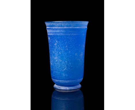 Ca. AD 1 - 100.A tall cobalt blue opaque glass beaker resting on a splayed foot. The body flares gently towards the opening a