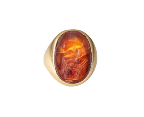 A large Roman carnelian intaglio set in a heavy antique gold ring Representing a young man, possibly a young Zeus, sitting do