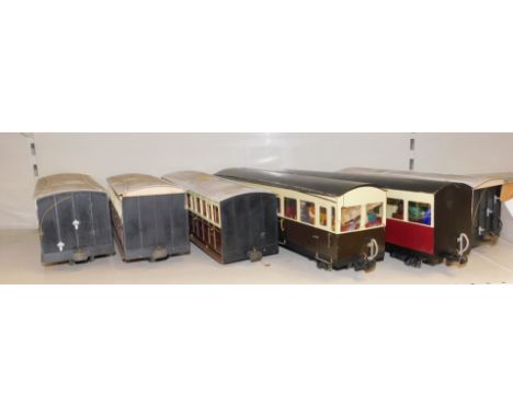 Six large scale model railway coaches, some containing figures, including GWR, together with a box of different, wider gauge 