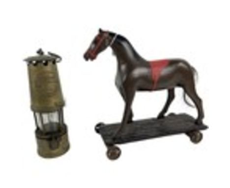 A composition Toy Horse, on rectangular wooden base with four cast iron wheels, 30cms (12"); together with a brass Oil lamp, 