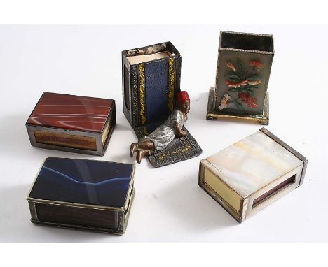 A PAINTED BASE METAL MATCH BOX HOLDER with an Arab boy on a carpet at the base, two plated agate-mounted match box holders, a